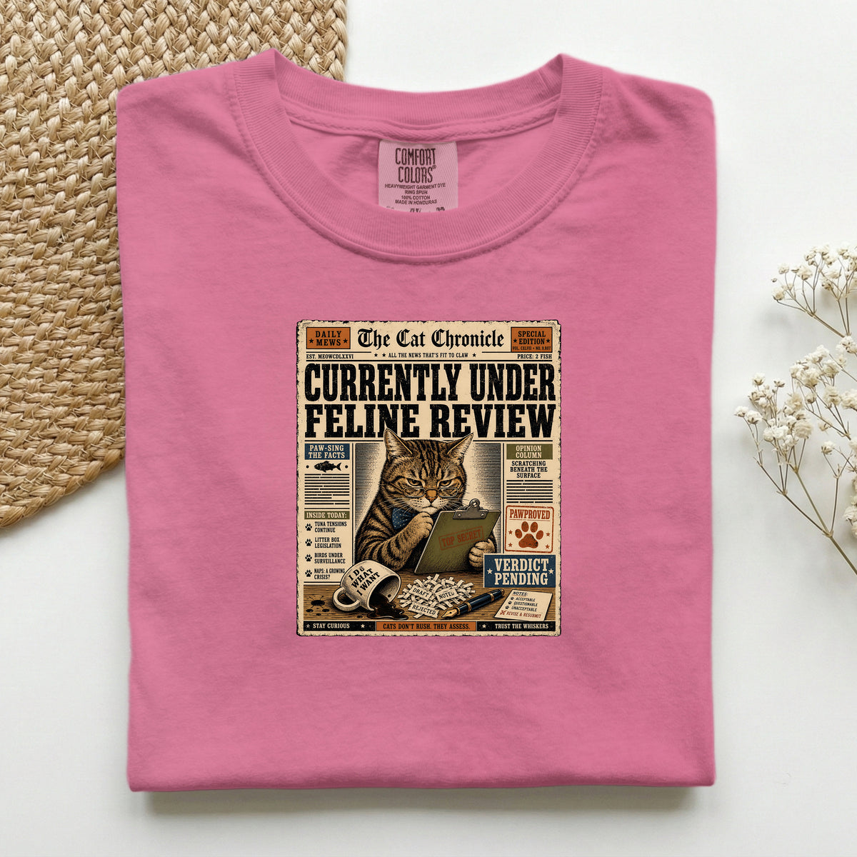 Currently Under Feline Review graphic tee in Crunchberry, folded mockup