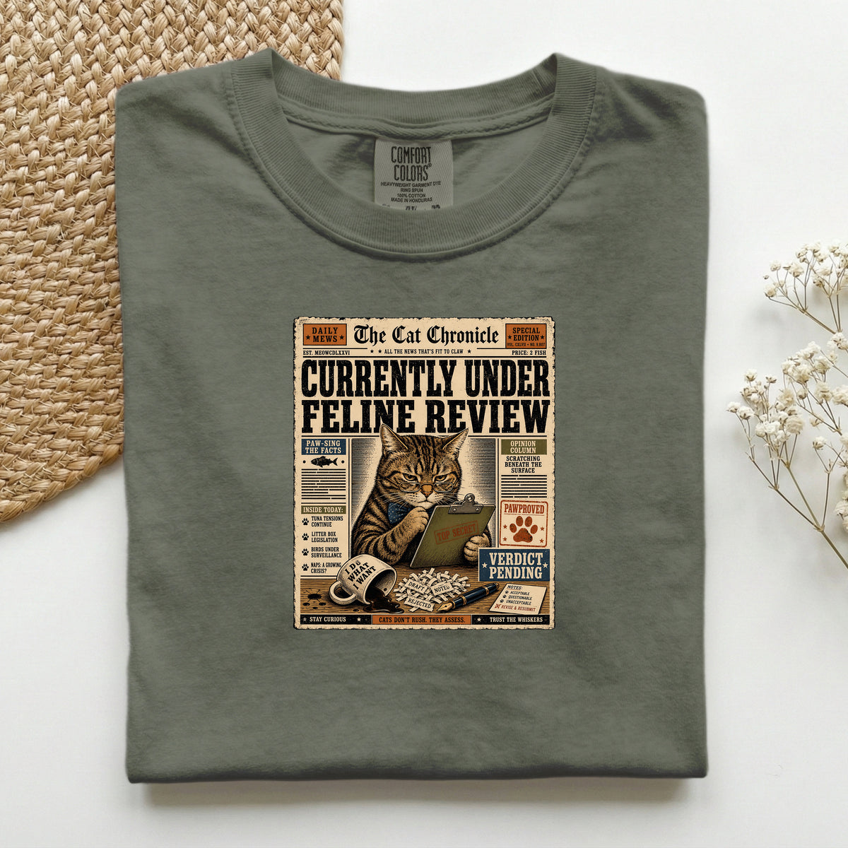 Currently Under Feline Review graphic tee in Moss, folded mockup