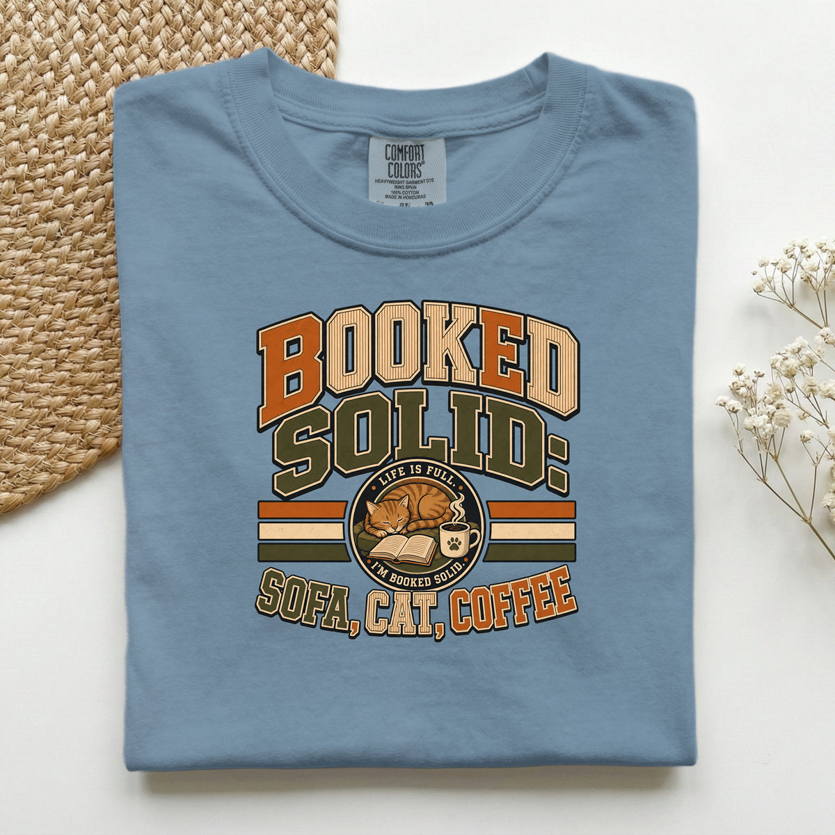 Booked Solid Sofa Cat Coffee graphic tee in Blue Jean, folded flat lay
