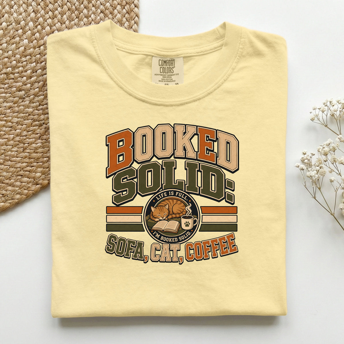Booked Solid Sofa Cat Coffee graphic tee in Butter, folded flat lay