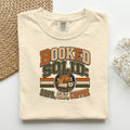 Booked Solid Sofa Cat Coffee graphic tee in Ivory, folded flat lay