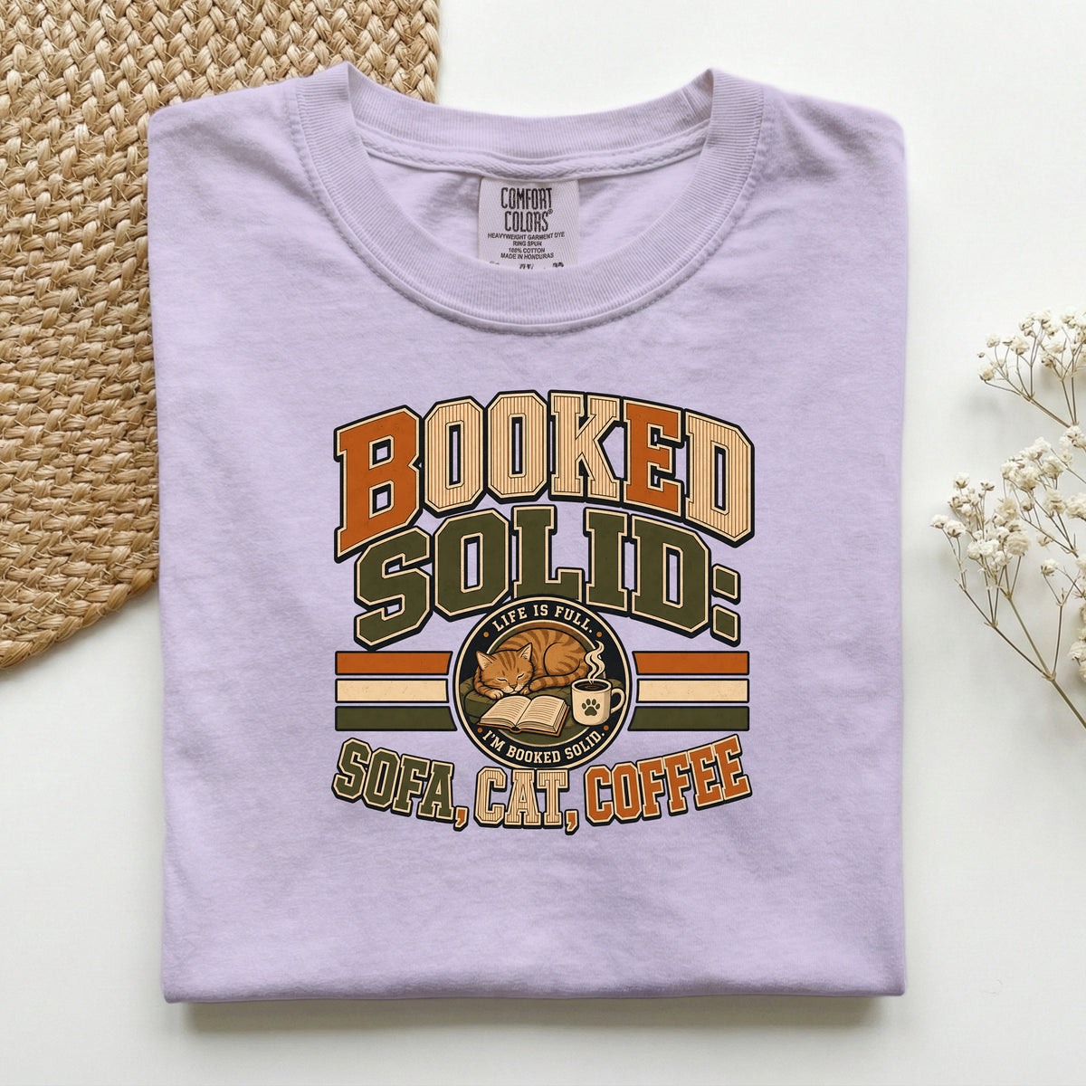 Booked Solid Sofa Cat Coffee graphic tee in Orchid, folded flat lay