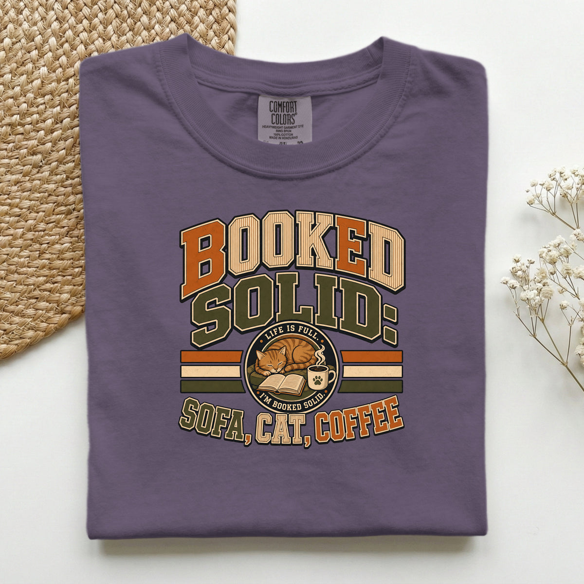 Booked Solid Sofa Cat Coffee graphic tee in Wine, folded flat lay