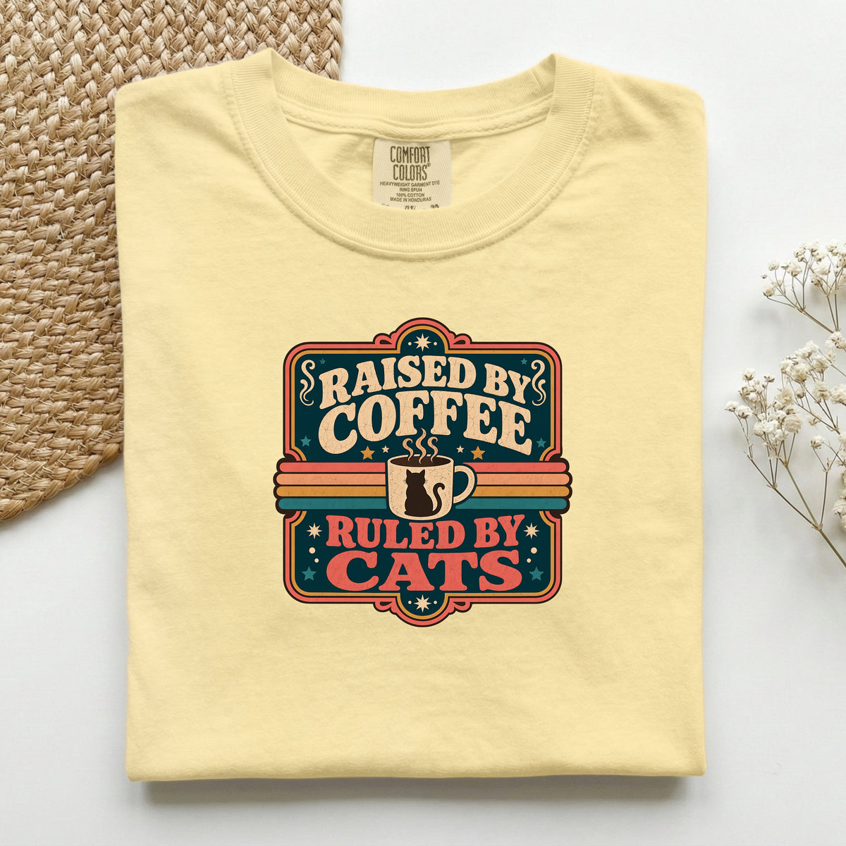 Raised By Coffee Ruled By Cats graphic tee in Butter, folded flat lay